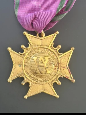 Amarant Ordern Medalj  - Amarant Ordern bildades av drottning Victoria runt år 1600 . Detta är Grad 1 medalj! Unik guldfärgad medalj i form av ett kors med texten 'MEMORIA PULCH' och initialerna 'WA' på framsidan. Baksidan har ingraverade årtal och text. Medaljen hänger i ett lila band med gröna ränder. Perfekt för samlare av militära eller historiska föremål.