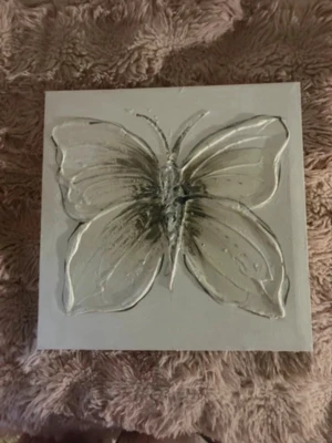Vit tavla med fjäril i relief - Säljer en fyrkantig vit tavla med en stor fjäril i relief. Fjärilen är detaljerad och har en 3D-effekt som gör att den sticker ut från bakgrunden. Perfekt som dekoration till rummet för en stilren och modern känsla.