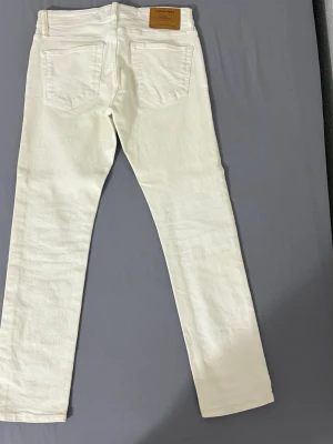 Vita raka jeans från Jack & Jones - Snygga vita jeans från Jack & Jones med rak passform och klassisk femficksdesign. Jeansen har knappgylf och är tillverkade i ett mjukt bomullstyg. Perfekta för dig som vill ha en clean och stilren look. Använda 3-4 gånger 