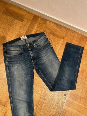 Mörkblå slim jeans från Acne Studios - Snygga mörkblå slim jeans från Acne Studios med klassisk femficksdesign och diskret slitning på låren. Jeansen har normal midja, slim passform och är tillverkade i stretchig denim för en bekväm känsla. Pris kan diskuteras