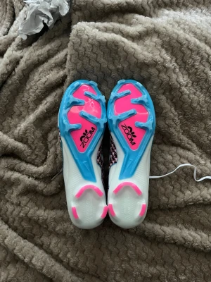 Nike Air Zoom Mercurial Vapor 15 Elite  - Säljer ett par helt nya Nike Mercurial Vapor 15 i toppmodellen Elite. Skorna ingår i "Mad Ready"-kollektionen och är i absolut nyskick – aldrig använda och har aldrig rört en fotbollsplan. Detta är Nikes absoluta toppsko, fylld med teknologi för maximal snabbhet och bollkänsla. Specifikationer: • Modell: Nike Air Zoom Mercurial Vapor 15 Elite FG (Firm Ground). • Storlek: 44 (28 cm). • Skick: 10/10 – Helt nya/oanvända. • Färg: White/Black/Casper Teal/Pink Blast. • Nypris: Ca 2 800 – 3 000 kr. 