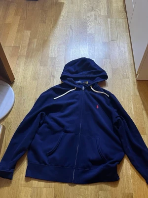 Marinblå hoodie från Polo Ralph Lauren - Snygg marinblå hoodie från Polo Ralph Lauren med dragkedja.