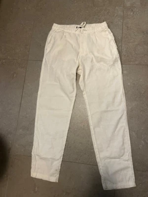 Beiga linnebyxor  - Snygga och avslappnade linnebyxor i beige med elastisk midja och dragsko. Byxorna har raka ben och sidofickor, perfekta för en chill och stilren look. Tillverkade i luftigt linne som känns skönt mot huden. Storlek xs-S passar båda 
