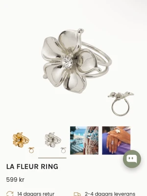 La Fleur Ring silverblommig ioaku - Snygg silverfärgad ring från La Fleur med stor blomformad design och en gnistrande sten i mitten. Ringen har en unik och iögonfallande stil som verkligen sticker ut. Perfekt för dig som gillar att uttrycka din personlighet med accessoarer. Lite missfärgning närmast diamanterna men inget som syns tydligt.