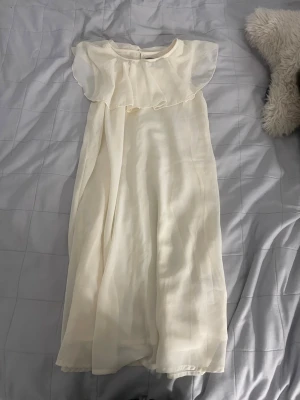 Vit volangklänning från Creamie - Söt vit klänning från Creamie med volangdetalj över axlarna och lätt, flödande tyg. Perfekt för sommarens alla tillfällen. Klänningen har en mjuk och luftig känsla och rund halsringning. Jätte snygg och gullig när du är brun och tan!🥰 