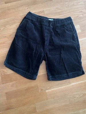 Svarta manchester shorts - Säljer ett par svarta manchester shorts med normal passform. Shortsen har bälteshällor, sidofickor fram och två bakfickor. Perfekta för dig som gillar en klassisk och avslappnad stil.