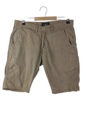 RRL Ralph Lauren beige shorts, storlek W30 - Klassiska beiga shorts från RRL Ralph Lauren i bomull. Modellen har två sidofickor fram och två bakfickor med knapp. Stängs med knapp och dragkedja. Perfekta för en avslappnad och stilren look. Midja: 40cm Långt: 25cm