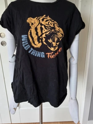 Svart t-shirt med tigertryck - Snygg svart t-shirt med ett stort tigertryck. T-shirten har rund hals och korta ärmar. Materialet är mjukt bomull. Säljer pga att den inte används och storleken kan upplevas som xs/s/m💓