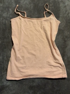 Ljusrosa  linnetopp med smala band - En enkel och stilren ljusrosa  linnetopp med smala axelband. Toppen har en rak passform och är tillverkad i mjuk bomull, perfekt för varma dagar eller som lager under andra plagg.