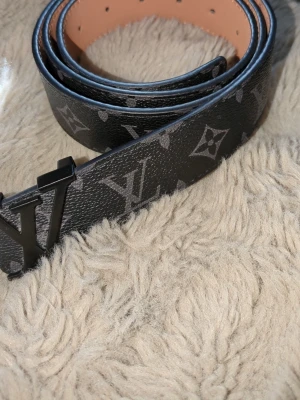 Svart bälte - Acceptabelt skick. Egengjord hål längst ut på bältet, missfärgning på baksidan