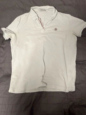 Moncler piké äkta - Tja säljer nu en äkta vit Moncler piké och storlek XL. Hör av dig vid frågor eller funderingar.