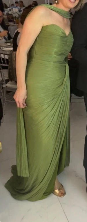 Grön omlott långklänning - Snygg grön långklänning med omlottdetalj och draperad effekt. Klänningen är axelbandslös och har en elegant, figurnära passform som ger en lyxig känsla. Perfekt för dig som vill sticka ut med en unik look.