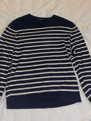 Marinblå randig tröja från Sunspel - Snygg marinblå tröja från Sunspel med vita horisontella ränder. Klassisk rund halsringning och långa ärmar. Tillverkad i Portugal och perfekt för dig som gillar stilrena basplagg med en twist.