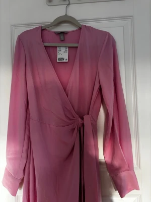 Rosa omlottklänning från H&M - Säljer en ljusrosa omlottklänning från H&M i storlek XS. 