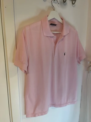 Ljusrosa pikétröja Polo Ralph Lauren - Ljusrosa pikétröja från Polo Ralph Lauren i mycket bra skick. Inga defekter eller slitage, en perfekt piké inför sommaren! Hör av er vid frågor!