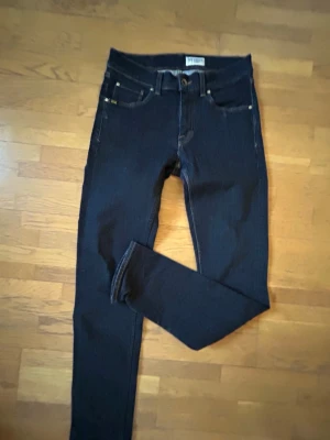 Mörkblå skinny jeans från Tiger of Sweden - Snygga mörkblå skinny jeans från Tiger of Sweden med klassisk femficksmodell och smal passform. Jeansen har detaljer i silverfärg och är tillverkade i stretchigt denimtyg för extra komfort. Perfekta för en trendig och stilren look.
