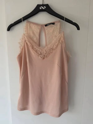 Ljusrosa spets linnetopp - Söt ljusrosa linnetopp med tunna axelband och v-ringning dekorerad med spets. Toppen har spets även i ryggen och en liten knappdetalj bak 💞Perfekt för en romantisk look och enkel att styla till olika outfits. Den var orginellt storlek XL men jag har sytt om axelbanden så att de nu är mycket kortare så att den sitter mer som S-M, men med en relaxed fit💗💗💗Se skick i bilderna