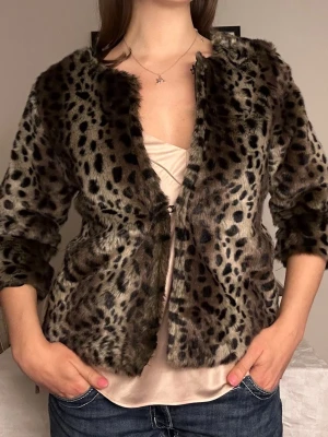 Leopardmönstrad pälsjacka med trekvartsärm🐆 - Säljer en snygg leopardmönstrad pälsjacka i fuskpäls med trekvartsärmar och öppen front. Jackan har en klassisk, rak passform och är perfekt för dig som vill sticka ut med en trendig look. Färgen går i brunt, beige och svart med tydligt djurmönster. Älskar denna!🐆