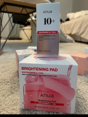 Anua Brightening Pad Niacinamide 5+TXA - Båda produkterna är helt obrutna/oöppnade/oanvända. Fortfarande förseglade. Anua Brightening Pad med niacinamide 5% och TXA är toner-pads som ger huden lyster och jämnar ut hudtonen. Förpackningen innehåller 60 pads och har en fräsch rosa och vit design. Perfekt för dig som vill ha glow och enkel hudvård.