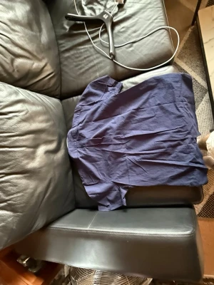 Mörkblå kortärmad skjorta i bomull - En enkel och stilren mörkblå skjorta i mjuk bomull. Skjortan har korta ärmar och klassisk passform, perfekt för en avslappnad look. Passar dig som gillar basic men ändå vill ha något snyggt och bekvämt.