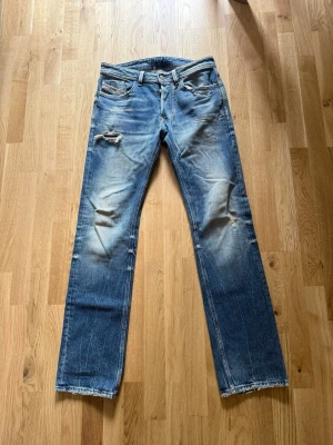 Blå slitna jeans från diesel - Säljer ett par blå jeans från diesel med slitningar. Perfekta för en avslappnad och trendig look.