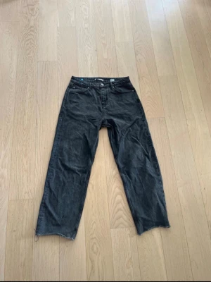 Svarta FSBN Jeans - Säljer ett par svarta jeans med rak passform och råa, avklippta benslut. Perfekta för en avslappnad och trendig look. Bra kvalite utan defekter.