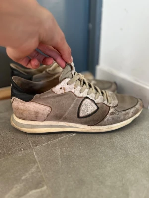 Beige sneakers från Philippe Model - Snygga beige sneakers från Philippe Model med svart detalj på hälen och vitt märke på sidan. Dessa skor gör dig ungefär 5 cm meter längre. Ser slitna ut men deras model är så men dem är använda, dock anser jag inte det som en problem då jag tycker det är snyggt och priset är även skit bra då det kostar 2500 i nypris!🫱🏻‍🫲🏼