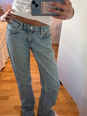 Ljusblå raka jeans från weekday - Säljer ett par ljusblå raka jeans från weekday med klassisk femficksmodell och låg midja. Jeansen har en avslappnad passform och är tillverkade i slitstark denim. Perfekta till en enkel topp eller hoodie för en cool vardagslook. Slitage vid hälarna (se bild)