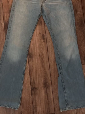 Ljusblå bootcut jeans från Lee - Säljer ett par ljusblå bootcut jeans från Lee med klassisk femficksdesign och Lee-lapp bak i midjan. Jeansen har en lätt tvättad look och raka ben med svag utsvängning. Perfekta för en avslappnad och trendig stil. Bra skick, enda difektern är lite kala trådar längst ner på byxorna, se bild 5-6. Storlek W29, L34
