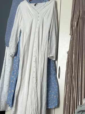 Vit långklänning med knappar - Säljer en elegant vit långklänning med v-ringning och långa ärmar. Superfin