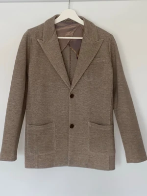 Beige kavaj med stickad känsla - Säljer denna snygga beigea kavaj från John Henric. I storlek xs i mycket bra skick.
