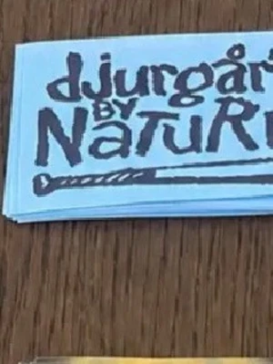 Blå tygmärke Djurgår'n by Natur - Säljer ett blått tygmärke med texten 'Djurgår'n by Natur' i svart tryck. Märket har en rektangulär form och är perfekt att sy fast på kläder, väskor eller andra accessoarer.