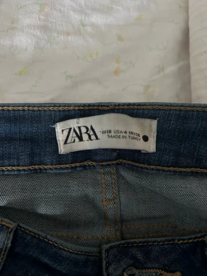 Blå raka jeans från Zara - Säljer ett par klassiska blå jeans från Zara med rak passform och normal midja. Jeansen har snygga kontrastsömmar och är tillverkade i denim. Perfekta för dig som gillar en enkel och tidlös look.