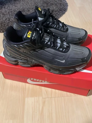 Nike Air Max Plus Tn Svart/Grå - Nike Air Max Plus Tn sneakers i svart och grå med ikoniska Tn-detaljer på plösen och sidan. Skorna har en futuristisk design med svarta och grå paneler, mesh- och syntetmaterial samt synlig Air Max-dämpning i sulan. Swoosh-logga på sidan och svarta skosnören.
