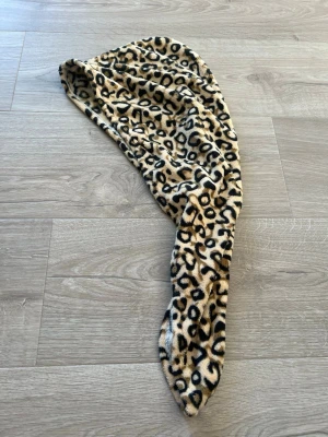 Leopardmönstrad hårturban - Säljer en fluffig hårturban i beige med svart och brunt leopardmönster. Perfekt för att svepa mothåret efter duschen. Tillverkad i mjuk, absorberande fleece som känns skön mot håret. Snygg accessoar för dig som gillar djurmönstrat.