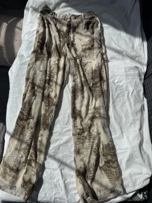 Byxor abstrakt mönster - Säljer ett par beige bruna byxor med abstrakt mönster. Byxorna har avslappnad passform. Tunn & flowy material som känns riktigt skönt mot huden. Perfekta för sommaren! Pris kan diskuteras! Gör en bundle!