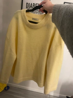 Gul stickad tröja från Gina tricot  - Mysig ljusgul stickad tröja från Weekday med rund halsringning och avslappnad passform. Tröjan har långa ärmar och ribbade muddar vid ärmslut och nederkant. Perfekt för lager på lager och enkel att styla till olika outfits.