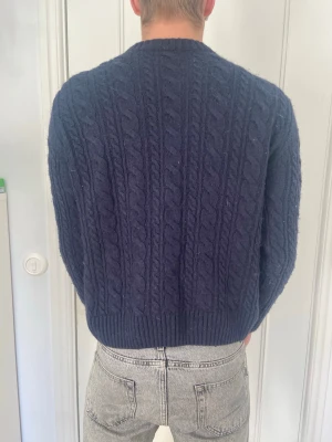 Mörkblå kabelstickad tröja -  mörkblå kabelstickad tröja från Zara med rund hals och ribbade muddar. Ganska liten i storleken Storlek M
