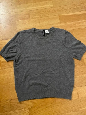 Mörkgrå kortärmad topp H&M - En enkel och stilren mörkgrå topp från H&M med korta ärmar och rund halsringning. Tillverkad i mjuk och tunn stickad kvalitet som känns skön mot huden. Använd en gång, ställ gärna frågor, kan dessutom skicka fler bilder om ni vill💕