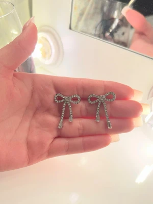 Glittriga rosettörhängen  - Säljer ett par söta örhängen i form av rosetter💓