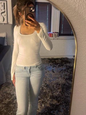 Vit långärmad topp med fyrkantig ringning - Säljer en enkel och stilren vit långärmad topp med fyrkantig ringning. Toppen är figurnära och passar perfekt till jeans eller kjol. Materialet känns mjukt och stretchigt, vilket gör den bekväm att bära hela dagen.