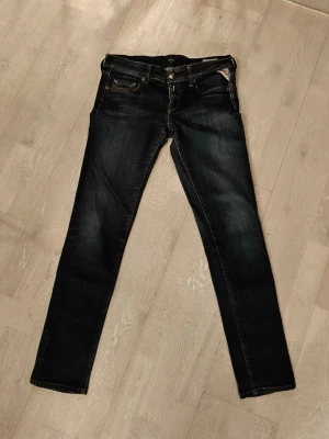 Mörkblå slim fit jeans med detaljer - Snygga mörkblå slim fit jeans med slitningar och kontrastsömmar. Klassisk femficksmodell med dragkedja och knapp i midjan. Bakfickorna har dekorativa sömmar. Perfekta för en trendig och avslappnad stil.