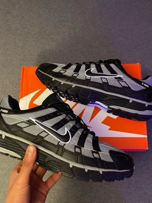 Nike P-6000 svart/grå sneakers - Nike P-6000 sneakers i svart och grått med mesh och syntetpaneler. Skorna har en chunky sula, vita detaljer och den klassiska Swoosh-loggan på sidan. Sportig design med coola detaljer och snörning framtill.