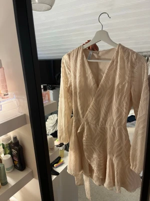 Ljus omlottklänning med strukturmönster - Supersöt ljus kortklänning med omlottdesign och v-ringning. Klänningen har även inbygga shorts 💕