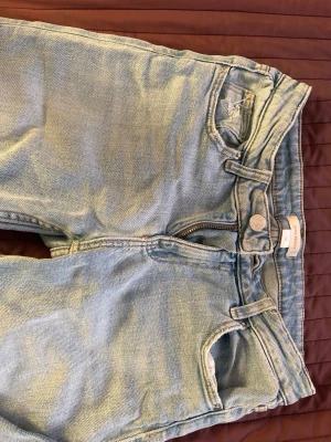 Ljusblå bootcut jeans från Gina Tricot - Säljer ett par ljusblå jeans från Gina Tricot , bootcut. Jeansen har klassiska fem fickor, bälteshällor och dragkedjegylf. Tillverkade i mjuk denim som ger en avslappnad look. Perfekta för dig som gillar vintagekänsla. Inga större tecken på användning, fläckarna går bort i tvätten!