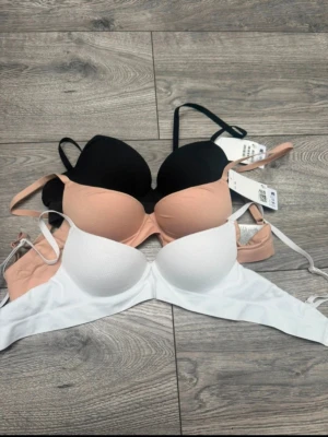 3-pack push up bhar i svart, vit och beige - Säljer ett 3-pack Push up bhar i färgerna svart, vit och beige. Alla har justerbara axelband och vadderade kupor för extra stöd och komfort. Materialet är mjukt och stretchigt, perfekt för en bekväm känsla hela dagen. Stilrena och enkla modeller utan spets eller extra detaljer.