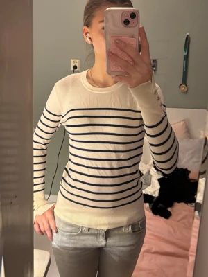 Randig tröja från Zara - Säljer en stilren långärmad tröja från Zara i vitt med mörkblå horisontella ränder. Tröjan har rund halsringning och är gjord i ett mjukt, tunt material som passar perfekt till jeans eller kjol 💗