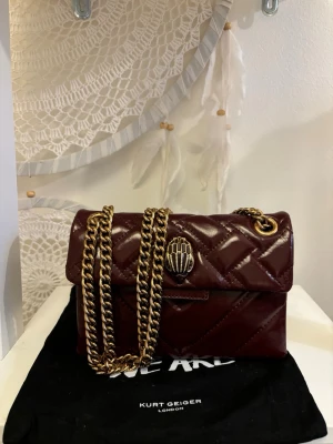 Vinröd quiltad handväska Kurt Geiger - Säljer denna vinröda handväska från Kurt gieger💕 den är använd ca 5 gånger och säljs för att den inte kommer till användning något mer den är köpt i london i deras egna butik och dustbad kommer med i köpet💕🤗