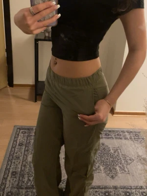 Olivgröna cargobyxor med resår - Säljer ett par olivgröna cargobyxor med resår i midjan och vid bensluten. Byxorna har stora sidofickor och är tillverkade i ett lätt och bekvämt tyg. Tyget känns lite som termobyxor. Dem passar bra fast dem är i så liten storlek. 