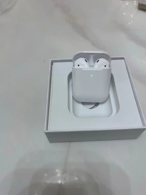 Apple AirPods med laddningsetui - Säljer ett par vita Apple AirPods med trådlöst laddningsetui. Snygg och stilren design i blank plast, perfekt för dig som vill ha smidiga hörlurar till mobilen. Kommer i originalförpackning med laddningskabel.